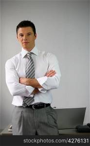 Serious businessman man by his desk arms folded
