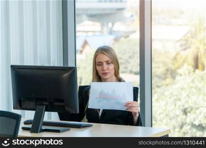 Serious caucasian businesswoman working at office desk, She looks tired bored and stressed. Concept of problems of new entrepreneurs are not able to successfully run a business