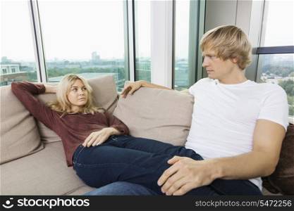 Serious couple looking at each other on sofa at home