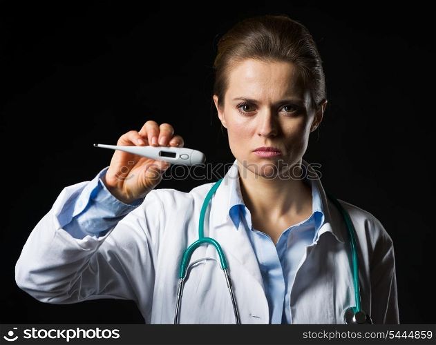 Serious doctor woman showing thermometer isolated on black