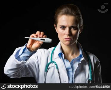 Serious doctor woman showing thermometer isolated on black