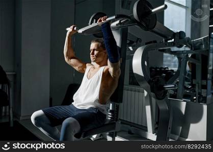 Serious exhausted man weightlifter working on training apparatus with barbell breathing hard. Sports man lifting heavy weights in gym. Serious exhausted man weightlifter working out with barbell