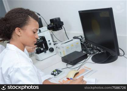 serious female scientist writing on her clipboard in her laboratory
