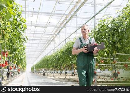Serious gardener carrying crate while walking in greenhouse