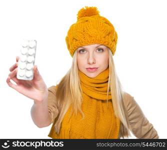 Serious girl in scarf and hat showing blister package of pills