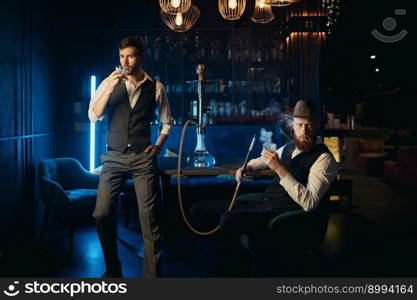 Serious guys smoking hookah while rest in a pub. Male bachelor mafia party in restaurant concept. Serious guys smoking hookah while rest in pub