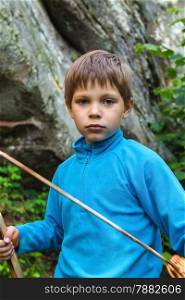 Serious kid with a wooden sword on stone