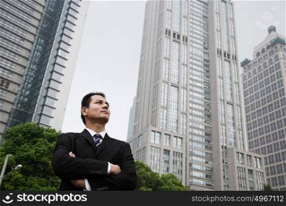 Serious looking businessman near skyscrapers