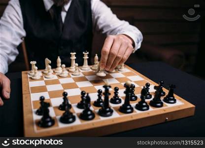 Serious male chess player in glasses makes victory move. Win strategy concept. Serious male chess player makes victory move