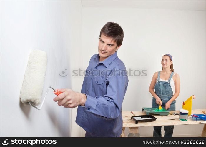 Serious man holding roller with woman in background