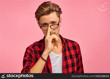 Serious man in glasses, pink background, emotion. Face expression, male person looking on camera in studio, emotional concept, feelings. Serious man in glasses, pink background, emotion