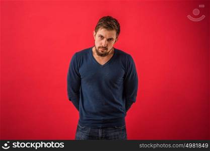 Serious man looking at camera standing against red background