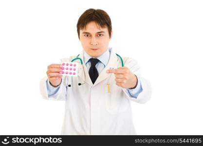 Serious medical doctor pointing finger at pack of pills isolated on white&#xA;