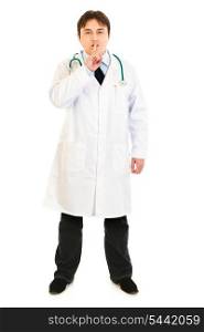 Serious medical doctor with finger at mouth isolated on white. Shh gesture&#xA;