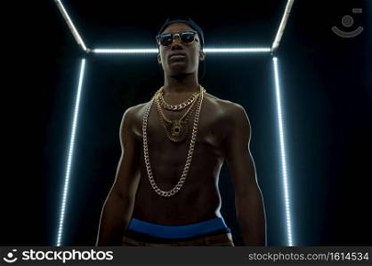 Serious rapper in gold chains, bottom view, dark background. Hip-hop performer, rap singer, break-dance performing, entertainment lifestyle, breakdancer. Serious rapper in gold chains, bottom view