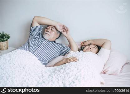 Serious senior couple looking away lying on bed 