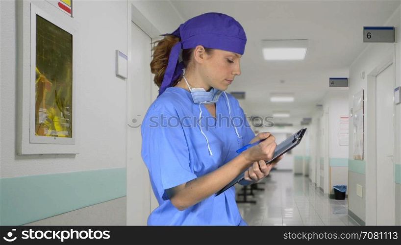 Serious surgeon with a cap and clipboard in hospital hallway