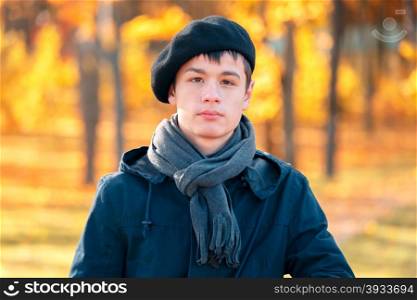 Serious teenage boy in the autumn sunny park. Serious teenage boy in a beret and jacket in the autumn sunny park