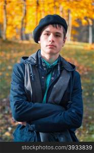 Serious teenage boy in the autumn sunny park. Serious teenage boy in a beret and jacket in the autumn sunny park