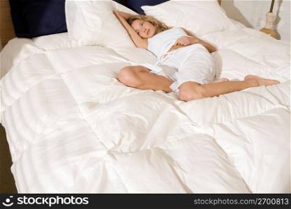 Serious woman laying on bed in bedroom in morning