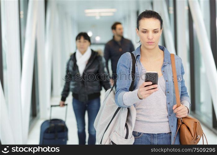 serious woman using smartphone at airport