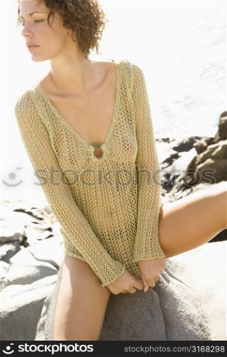 Serious young adult Caucasian female in transparent shirt looking off to side.