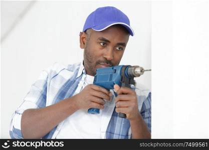 serious young builder handyman working with electric drill indoors