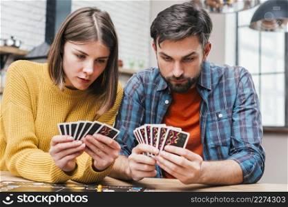 serious young couple looking their cards playing board game