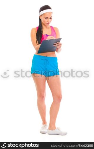 Serious young fitness trainer making notes in training plan isolated on white &#xA;