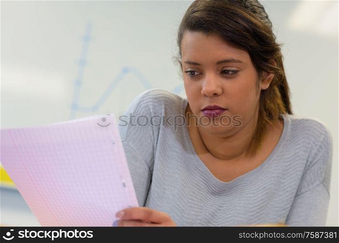 serious young lady in class looking at sheet of paper