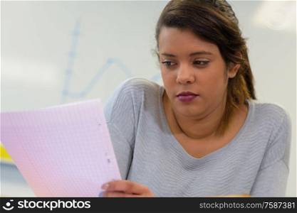 serious young lady in class looking at sheet of paper