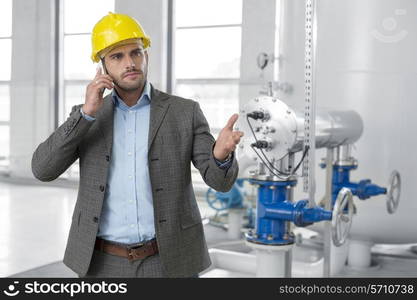 Serious young male manager using cell phone in industry