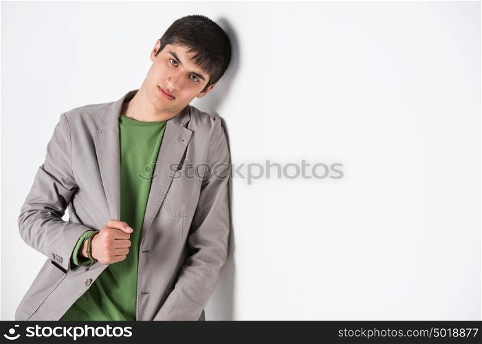 Serious young man leaning against white wall with copy space an the right