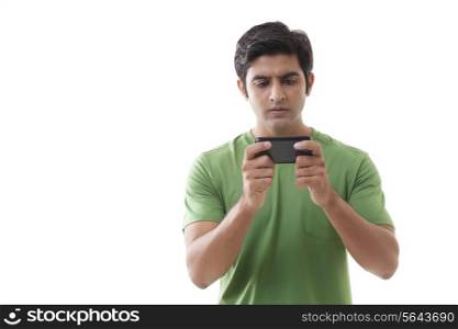 Serious young man reading text message over white background