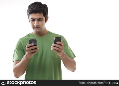Serious young man text messaging over white background
