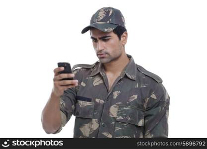 Serious young soldier reading message on his cell phone