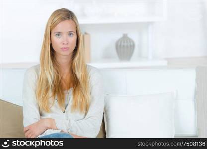 serious young woman sat at home on the sofa