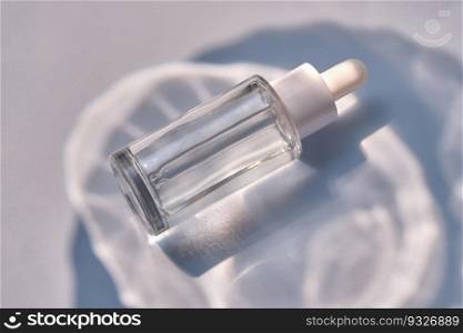 Serum bottle on a blue background. A perfect demonstration of the moisturizing properties of a serum.. Serum bottle on a blue background with glare.