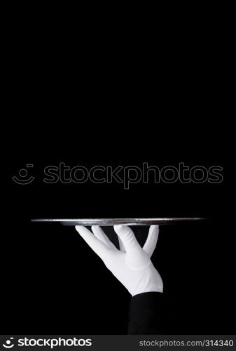 Servant wearing white glove holds stainless steel tray on black background