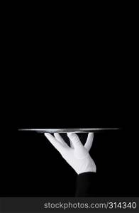 Servant wearing white glove holds stainless steel tray on black background