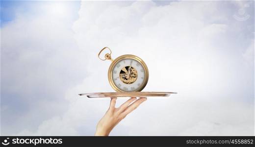 Serve time on tray. Waiter holding silver platter with old pocket watch