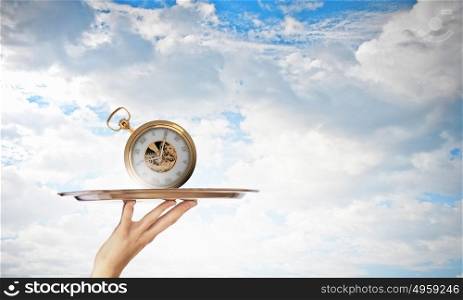 Serve time on tray. Waiter holding silver platter with old pocket watch