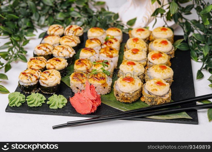 Served warm sushi with ginger and wasabi on a black stone plate