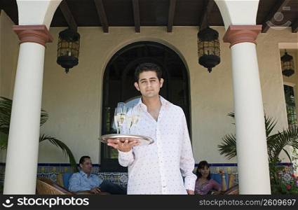 Server holding tray of champagne outdoors