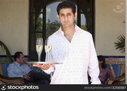 Server holding tray of champagne outdoors