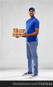 service and people concept - happy indian delivery man with food and drinks in blue uniform over grey background. happy indian delivery man with food and drinks