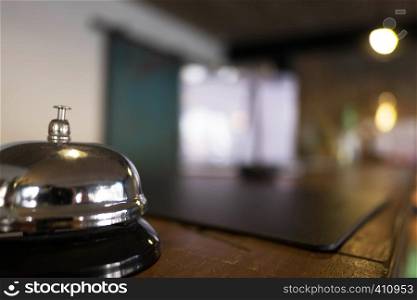 Service bell locating at reception. Silver call bell on table, receptionists on background.