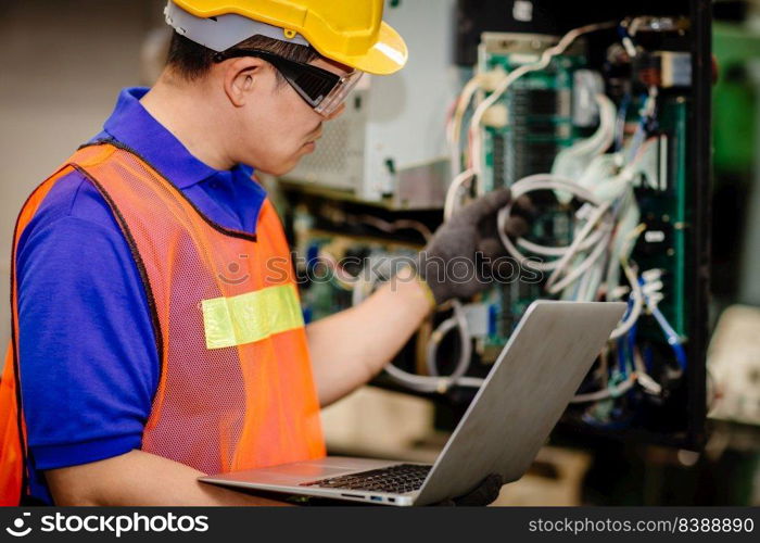 Service engineer team working with electronic wire back panel of heavy industry machine for maintenance repair and fix with laptop computer for analysis problems.