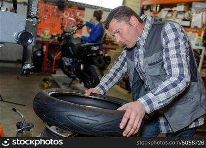 service mechanic with installer replace tyre on wheel in workshop