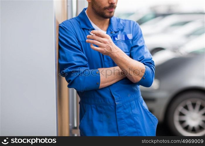 service, repair, maintenance and people concept - close up of auto mechanic smoking cigarette. close up of auto mechanic smoking cigarette